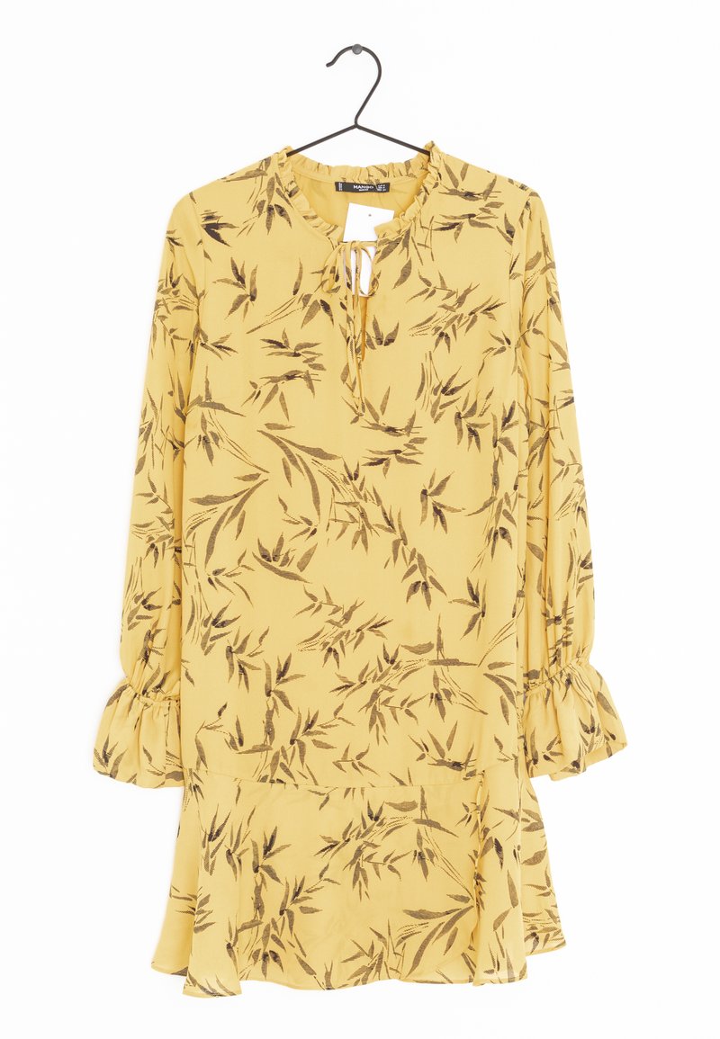Keltainen mekko, jossa on ruskea kukkakuosi, pitkät hihat, röyhelöhiha ja avainaukko-kaula-aukko. Valmistettu kevyestä kankaasta, lentävä muotoilu.