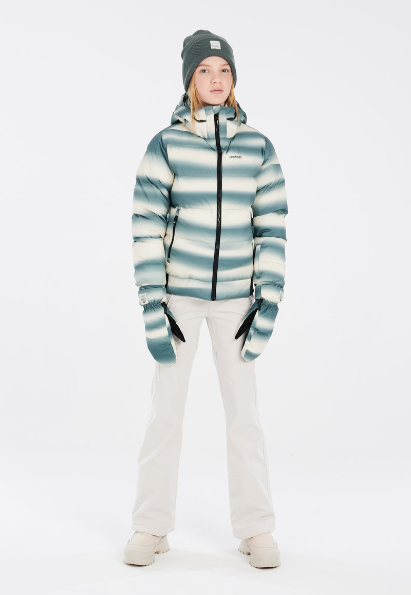 Gepolsterte Jacke mit einem blauen und cremefarbenen Streifenmuster, schwarzem Reißverschluss und Kapuze. Kombiniert mit weißen Hosen und abnehmbaren Handwärmern.