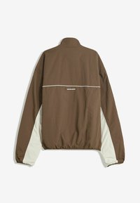 Brown windbreaker jacket with a high collar, elastic hem, and white side accents. Features a logo on the upper back in white text.