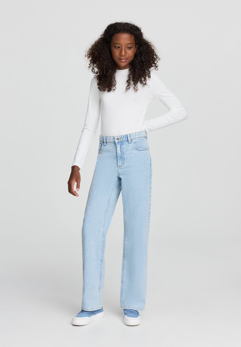 Jeans azzurri chiari a vita alta con una vestibilità rilassata, leggero sbiadimento, tasche frontali e una cintura con chiusura a bottone metallico.