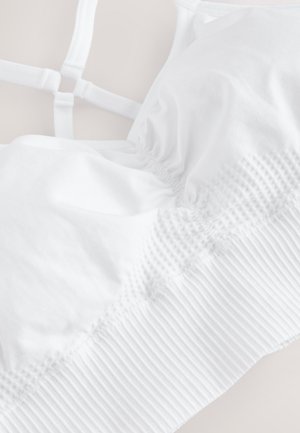 Hvid bralette med justerbare stropper, der har en tekstureret samling i midten og et ribbet bånd for støtte. Glat stof finish.