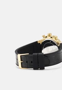 Schwarzes Lederarmband mit goldfarbener Schnalle und Krone. Das Armband hat ein strukturiertes Design und kontrastierende glatte Bereiche.