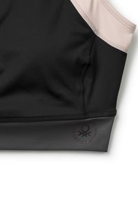 Černá a šedá sportovní podprsenka s měkkým materiálem, elegantním designem, kontrastními světle růžovými akcenty a logem na dolním okraji.