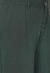 Mörkgröna, lätta byxor med en slät struktur, utrustade med knappstängning, elastisk midja och sidofickor. Enkel design, inga mönster.