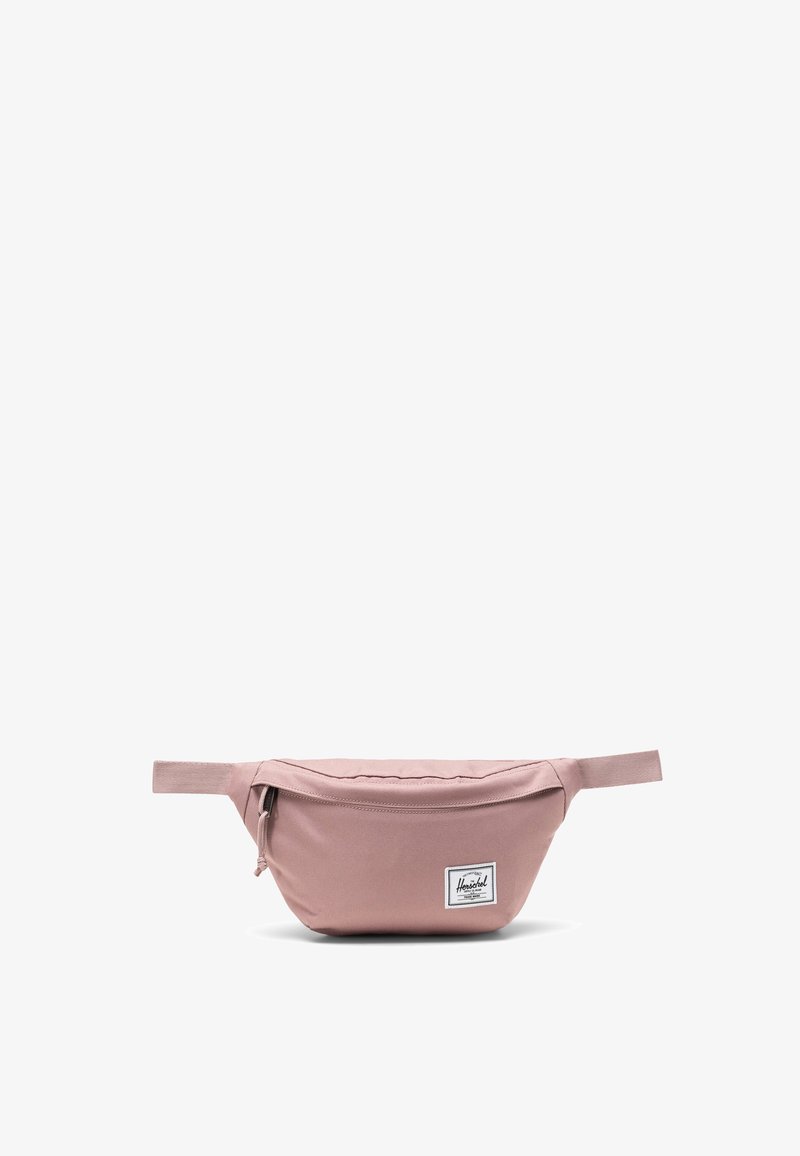 Růžová látková ledvinka s zakřiveným tvarem, horním zipovým uzávěrem a přední nášivkou s logem. Nastavitelný popruh a hladká textura.