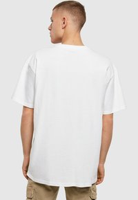 Hvit oversized t-skjorte laget av bomull, med korte ermer, rund halslinje og en enkel, glatt tekstur. Ingen synlige mønstre eller detaljer.