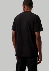 Camiseta de algodón negra con mangas cortas y cuello redondo estándar, con una textura suave y un corte relajado.
