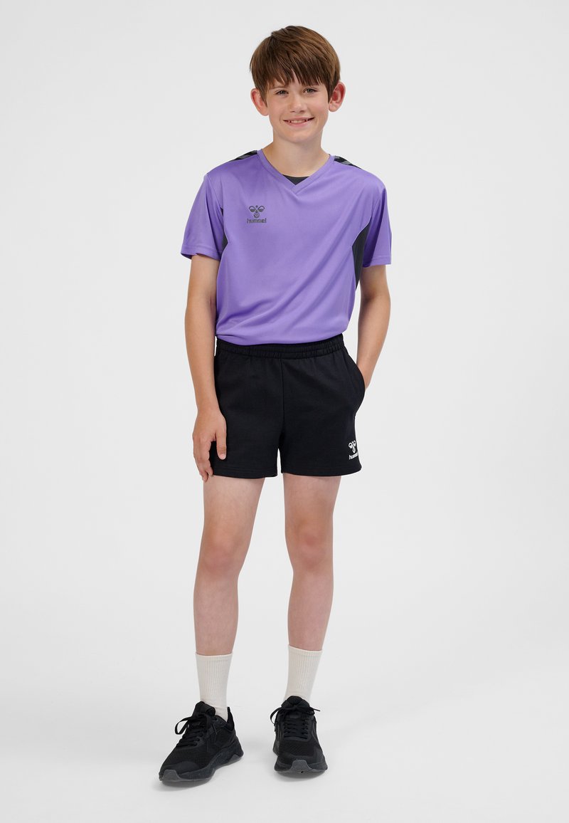 Maglietta sportiva viola a maniche corte con accenti neri, abbinata a pantaloncini neri. Scarpe nere e calzini bianchi visibili. Logo su maglietta e pantaloncini.