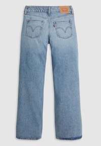 Jean en denim bleu clair avec jambes droites, deux poches arrière avec surpiqûres arquées, un patch en cuir marron de la marque et un onglet rouge Levi's.