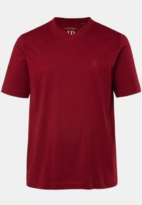 Camiseta de algodón rojo con cuello en V, presenta mangas cortas, un corte regular y un sutil logo en el pecho. Textura suave, diseño sencillo.