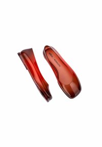 Bailarinas translúcidas rojas con punta redondeada y textura suave. Su diseño ligero cuenta con una suela plana y flexible con una sutil marca en el interior.