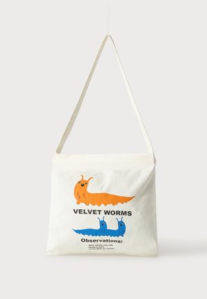 Weiße Tragetasche mit orangefarbenen und blauen Cartoon-Samtwürmern und Text, der ihre weichen, gruppenjagenden und schleimverwendenden Merkmale aufzählt.