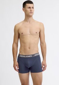 Mornarsko plave gaće s prilagođenim dizajnom, elastičnim pojasom koji prikazuje "JACK & JONES" brendiranje u bijeloj i narančastoj boji, izrađene od mekog materijala.