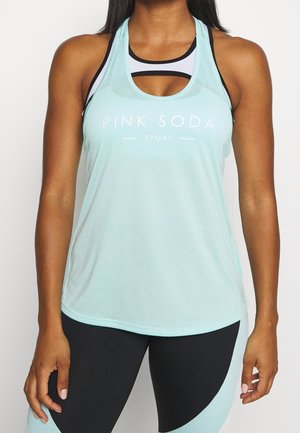 Žena nosí světle modrý top "Pink Soda Sport" přes černo-bílou sportovní podprsenku, doplněnou černo-modrými legínami.