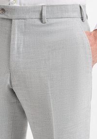 Helle graue Hose mit strukturiertem Muster, ausgestattet mit einem Knopfverschluss, Gürtelschlaufen und seitlichen Taschen für eine maßgeschneiderte Passform.