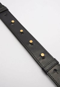 Cintura in pelle nera con borchie in metallo dorato; presenta una superficie liscia, forma rettangolare e due chiusure a scatto regolabili.
