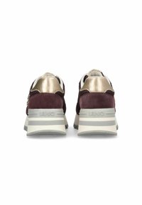 Baskets en suede bordeaux foncé avec des accents métalliques dorés, un col rembourré blanc et une épaisse semelle en caoutchouc grise avec un motif à rayures.