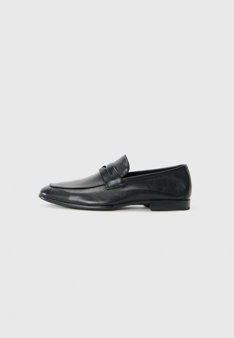 Black leather loafers featuring a rounded toe, stitched detailing, wide strap across the vamp, and a low, flat heel. Smooth finish.