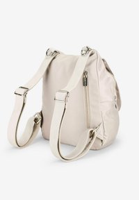 Mochila de nailon beige con correas ajustables duales, herrajes plateados, un bolsillo lateral con cremallera y un acabado suave y texturizado.