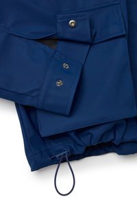 Veste imperméable bleu marine présentant une poche à pression, un cordon élastique à l'ourlet et une texture lisse avec des détails de couture.