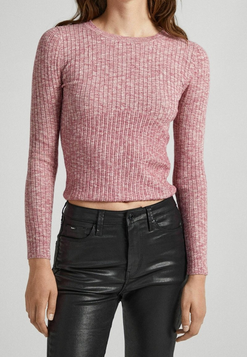 Maglia a maniche lunghe rosa a coste con scollatura rotonda, design aderente e lunghezza cropped, abbinata a pantaloni neri aderenti.