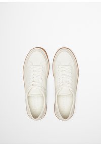 Helle cremige Leder-Sneaker mit runden Zehen, weißen Schnürsenkeln und braunen Gummisohlen. Minimalistisches Design mit eingeprägtem Logo auf der Zunge.