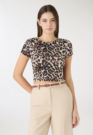 Top aderente a maniche corte con motivo leopardato beige e nero, realizzato in tessuto liscio. Abbinato a pantaloni crema e cintura marrone.