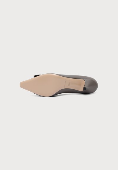 Chaussure plate grise à bout pointu vue par le dessous avec une semelle beige et un petit talon noir.