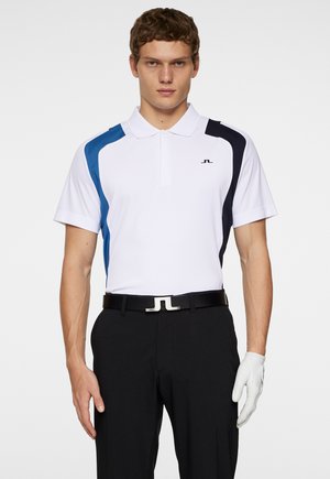 White polo shirt with blue and navy side panels, short sleeves, and a collar. Worn with black pants and a belt featuring a silver accent. White golf glove on hand.