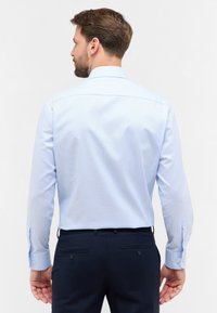 Lichtblauwe gestreepte lange mouwen shirt met een klassieke kraag, knopen bij de manchetten en een soepele textuur, gecombineerd met donkere broeken.