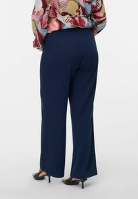 Pantalons larges bleu marine en tissu lisse et extensible, avec un design simple sans motifs ni embellissements visibles.
