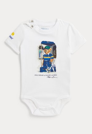 Body blanc pour bébé avec un ours imprimé en tenue bleue et jaune tenant un sac, avec le texte "Polo Bear by Ralph Lauren" en dessous.