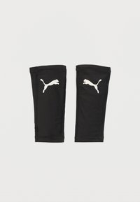 Ζεύγος μαύρων αθλητικών καλτσών μοσχαριού με λευκά λογότυπα Puma σε απλό λευκό φόντο.