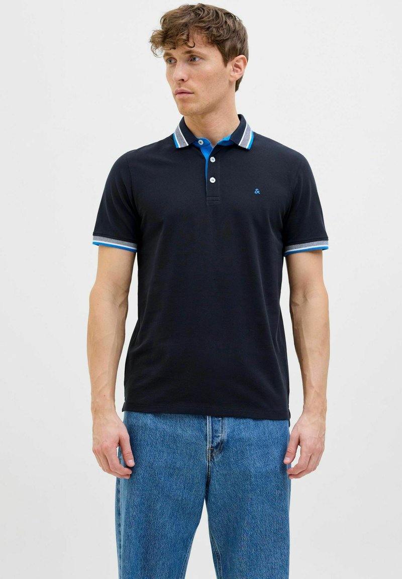 Marineblauwe polo met korte mouwen. Voorzien van een contrasterende kraag en mouwboorden in blauw en grijs gestreept. Drieknoopsluiting, logo op de borst.