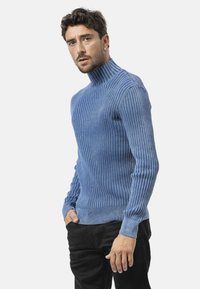 Geribbelde turtleneck trui in lichtblauw, gebreide stof met lange mouwen en een aansluitende silhouet, gecombineerd met zwarte broek.