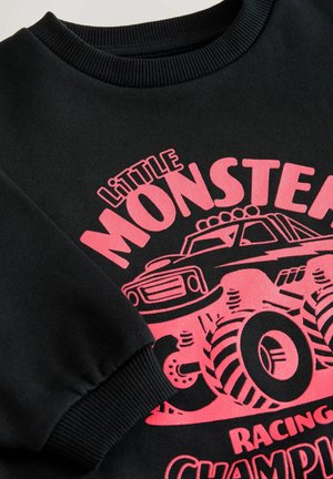 Black sweatshirt featuring a ribbed neckline and long sleeves, with a bright pink graphic of a monster truck and text detailing.
