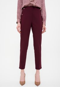 Bordeaux tapered broek met zijknopen, een gladde textuur en een op maat gemaakte pasvorm, gecombineerd met een gedessineerde top.
