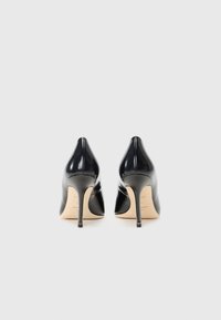Musta lakattu nahkainen korkokenkä, jossa on terävä kärki ja hoikka stiletto-korko, joka tarjoaa sileän, kiiltävän pinnan ja minimalistisen muotoilun.