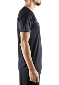 Camiseta atlética negra hecha de tejido suave. Mangas cortas, escote redondo, diseño ajustado, logo sutil en el pecho. Vista lateral mostrada.