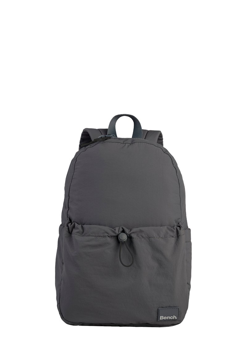 Sac à dos en tissu gris avec une forme arrondie, fermeture à cordon à l'avant, poche unique et bretelles réglables. Dispose d'un écusson de marque à la base.