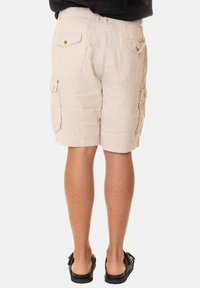 Pantaloni cargo beige con due tasche frontali, due tasche laterali e due tasche posteriori. Il tessuto ha un aspetto leggero e texturizzato.