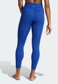Leggings sportivi blu con finitura testurizzata, vita alta e taglio alla caviglia. Presentano un logo sulla parte posteriore della vita.