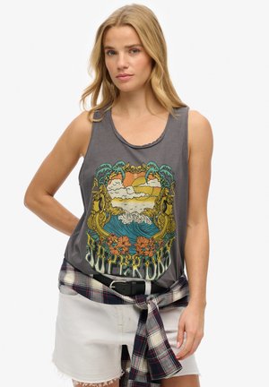 Débardeur gris sans manches avec un design graphique coloré représentant des vagues, des palmiers et des fleurs. Porté avec un short blanc et une ceinture à carreaux.