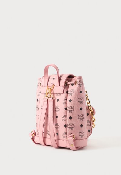 Sac à dos MCM en cuir rose avec motif logo noir, garnitures dorées, bretelles ajustables et poignée supérieure sur fond blanc.
