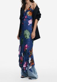 Sininen kukkamekko, jossa on röyhelöhelma ja moniväriset kukkakuviot. Yhdistetty mustan takin ja leveälahkeisten farkkujen kanssa.