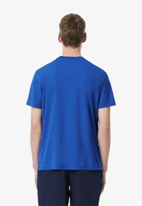 Camiseta azul de manga corta con cuello redondo. Textura suave y ajuste relajado, con un pequeño acento de la marca cerca del dobladillo.
