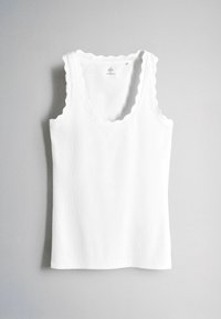 Débardeur blanc côtelé avec bords festonnés sur l'encolure et les emmanchures, présenté à plat sur un fond gris clair.