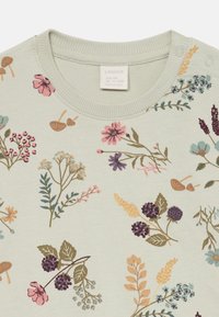 Helles grünes Babykleidungsstück mit Rundhalsausschnitt, Schulterdruckknöpfen und mehrfarbigem Blumen- und Beerenmuster.