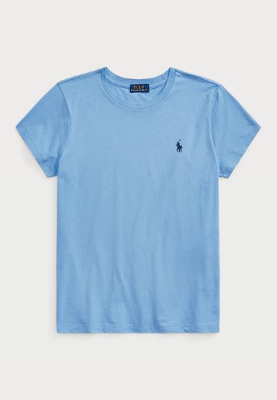 Svetlo modra kratkotrajna majica iz mehke bombažne tkanine. Ima krojen ovratnik in majhen mornarsko modri logo na levi strani prsnega koša. Gladka tekstura.