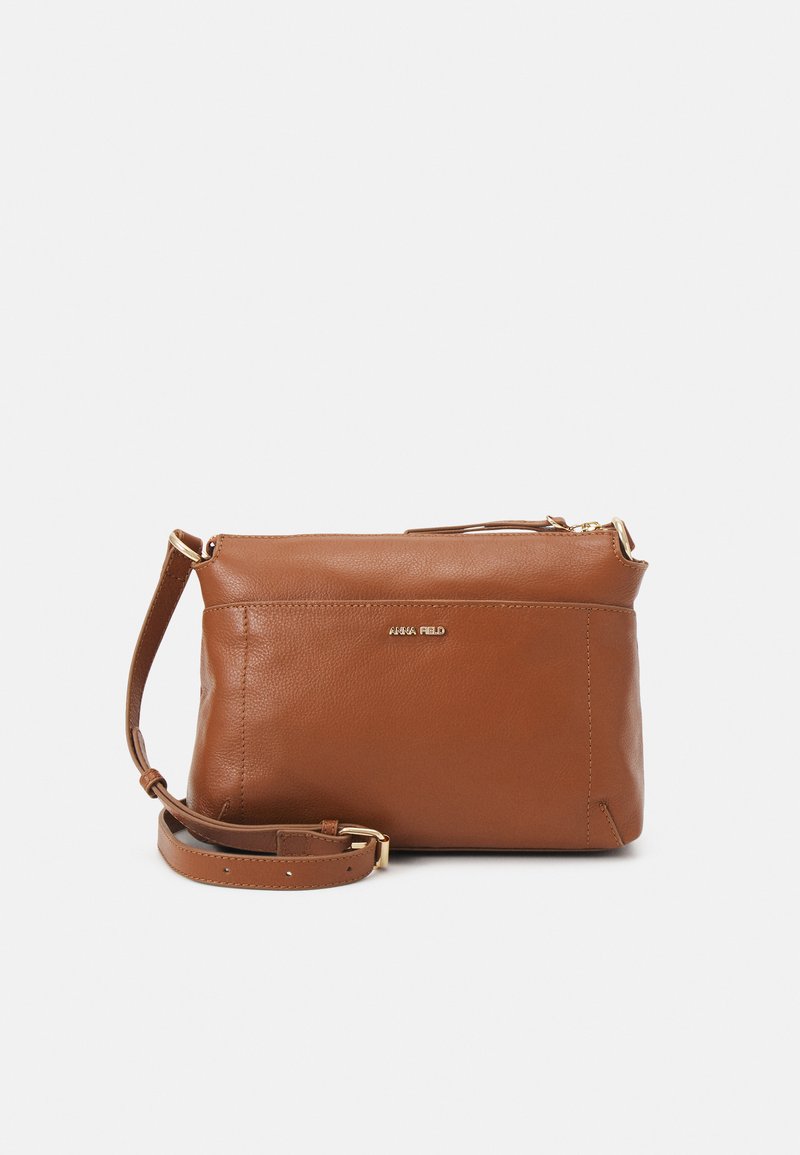 Brown leather crossbody bag with a smooth texture, golden hardware accents, and a zip closure. Adjustable strap attached.